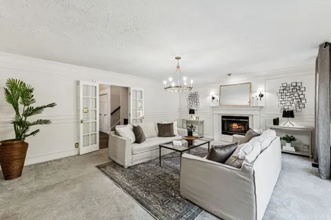 a living room with furniture large windows and a chandelier