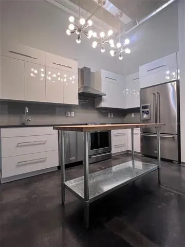 a kitchen with kitchen island stainless steel appliances a stove refrigerator and cabinets