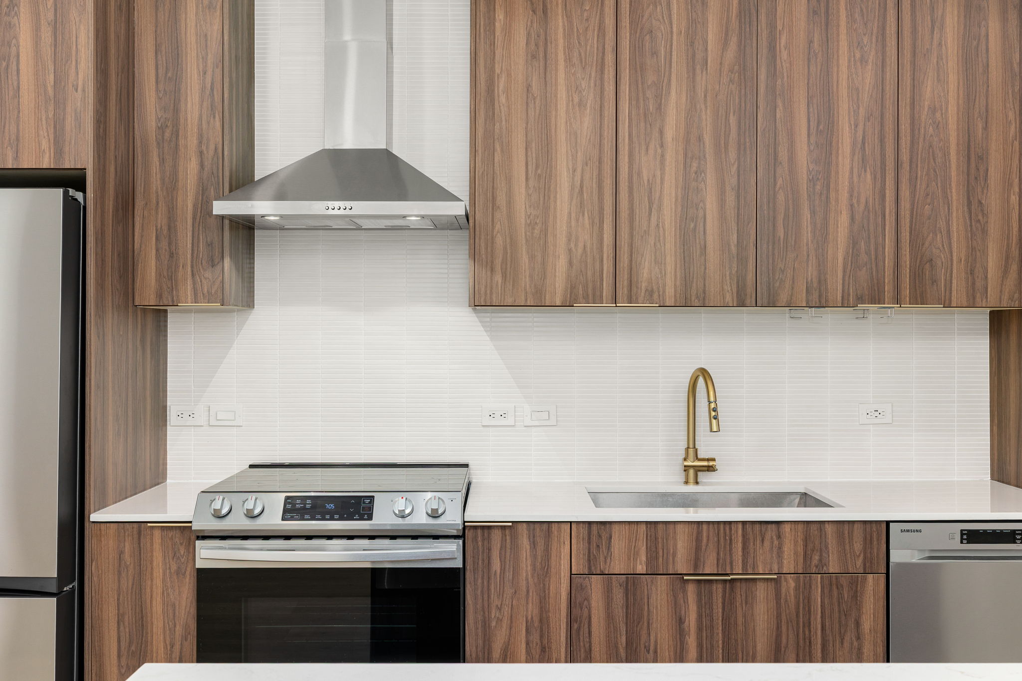 1701 Simond Avenue, Unit 612 Austin, TX 78723 - Photo 13 of 40 Kitchen featuring wood-finish cabinetry, stainless steel appliances, a brass-finish faucet, white subway tile backsplash, and light-tone countertops