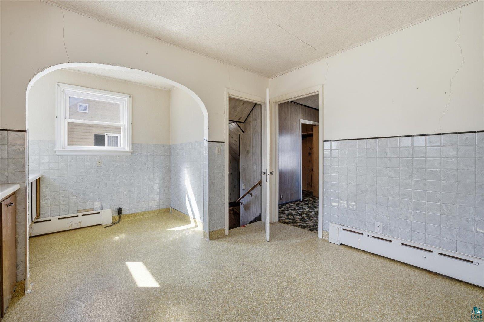 709 Michigan Street Hibbing, MN 55746 - Photo 8 of 47 Unfurnished room with wainscoting, tile walls, and a baseboard radiator