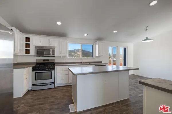 a kitchen with stainless steel appliances granite countertop a stove top oven a sink and a refrigerator