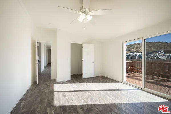 an empty room with wooden floor and a ceiling fan