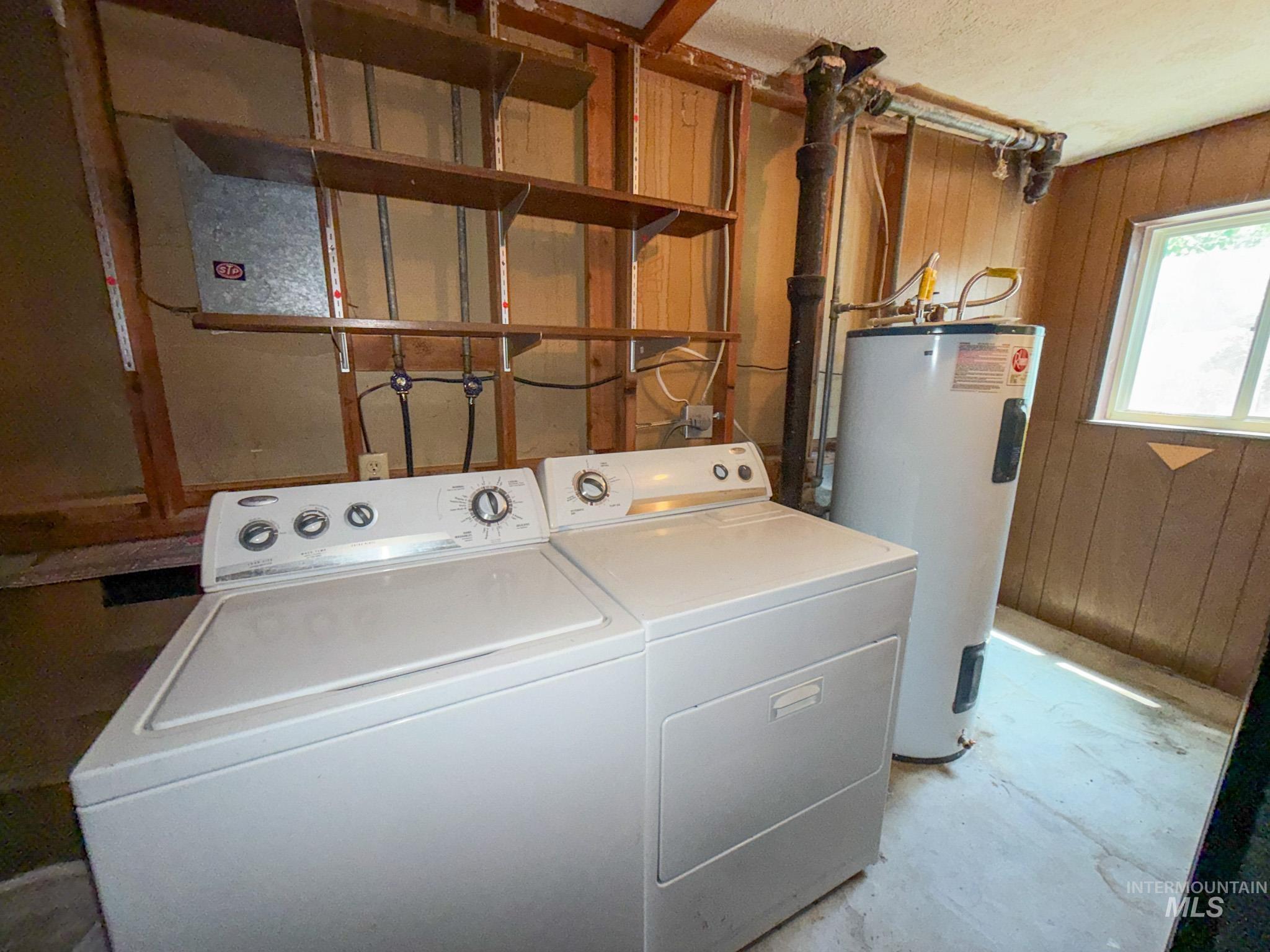 1924 H Street Rupert, ID 83350 - Photo 11 of 13 Dedicated laundry area featuring a washer and dryer, water heater, wood-paneled walls, and a window