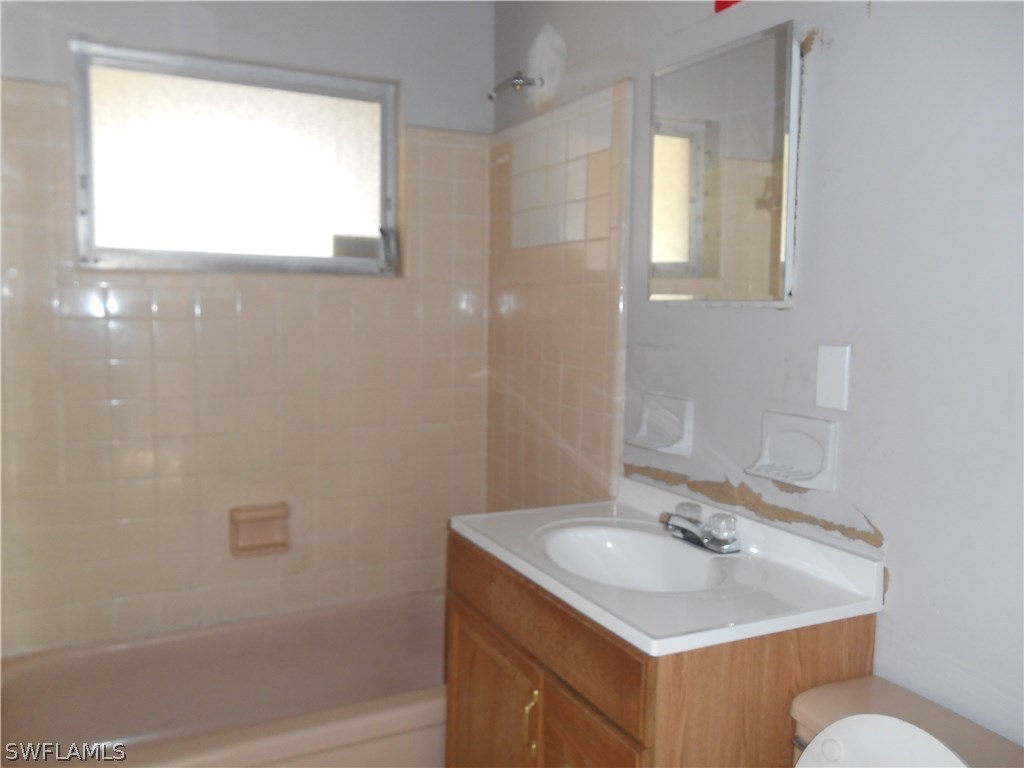 512 Wyoming Road Lehigh Acres, FL 33936 - Photo 8 of 17 a bathroom with a sink toilet a mirror and shower
