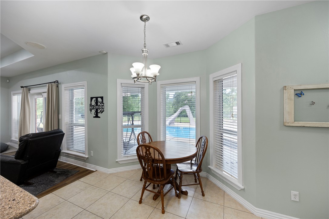 751 Walthall Road Russellville, AR 72802 - Photo 14 of 60 Bright dining area featuring a chandelier, tile flooring, and multiple windows offering exterior views of a pool