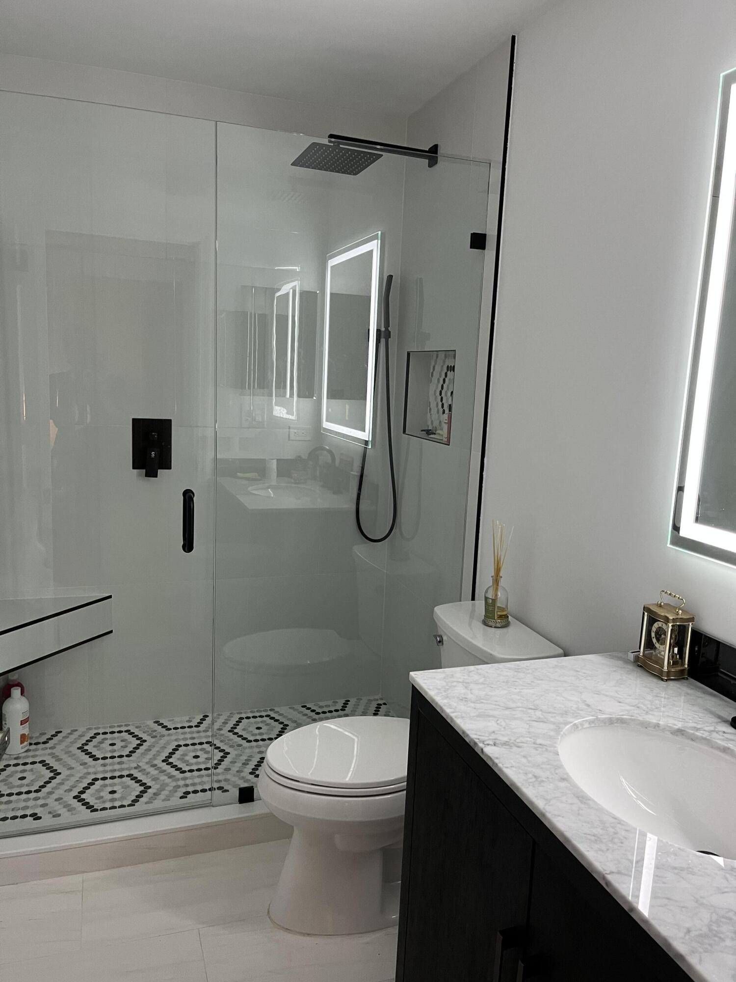 1001 Crystal Way, Unit A Delray Beach, FL 33444 - Photo 8 of 10 a bathroom with a granite countertop sink a toilet and shower