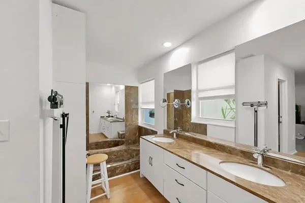 a bathroom with double vanity sinks a toilet a mirror and a shower