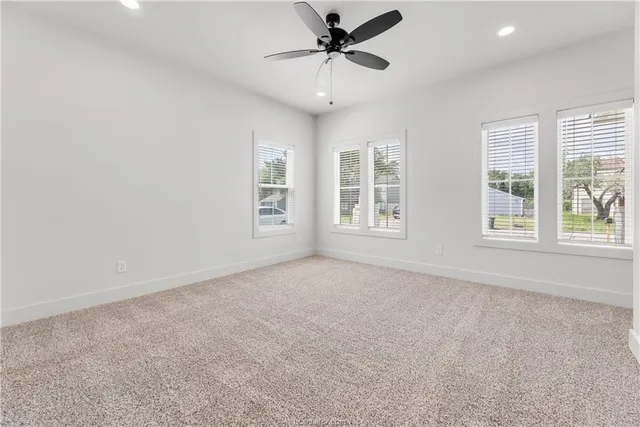 an empty room with windows and ceiling fan