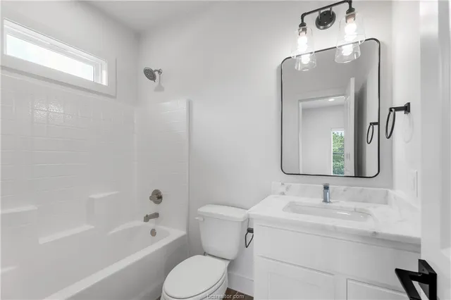 a bathroom with a toilet a sink a mirror a bathtub and vanity