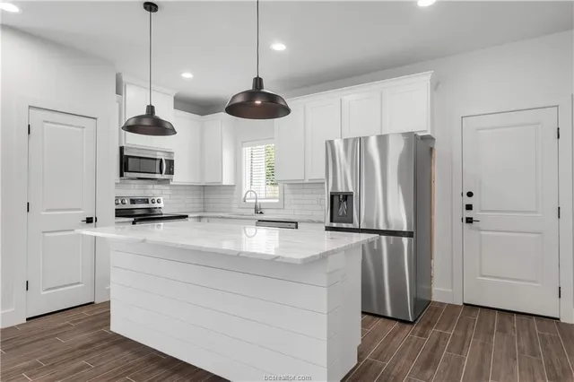 a kitchen with stainless steel appliances granite countertop a refrigerator a sink and a stove