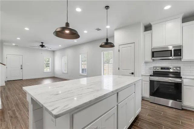 a kitchen with stainless steel appliances granite countertop a sink a stove and a wooden floors