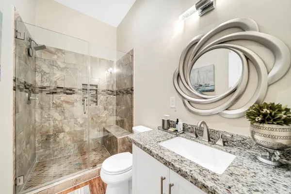 a bathroom with a granite countertop toilet a sink and a mirror