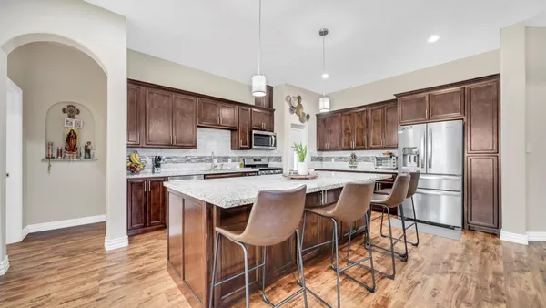 a kitchen with stainless steel appliances granite countertop a refrigerator a stove top oven a sink dishwasher and white cabinets with wooden floor