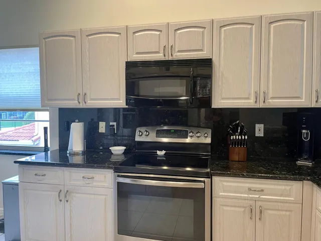 a kitchen with granite countertop white cabinets and stainless steel appliances