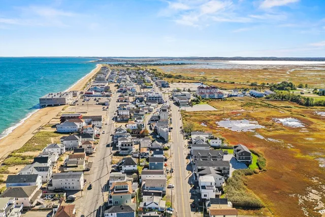 an aerial view of ocean and residential houses with outdoor space