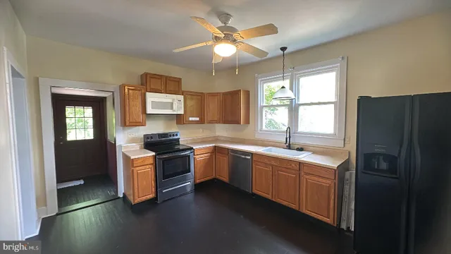 a kitchen with stainless steel appliances granite countertop a sink a stove a refrigerator a microwave oven with wooden floor and cabinets