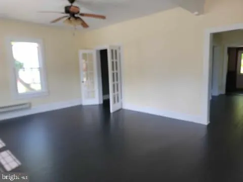 an empty room with wooden floor fan and windows