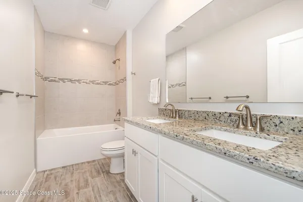 a bathroom with a granite countertop sink a toilet and a large mirror