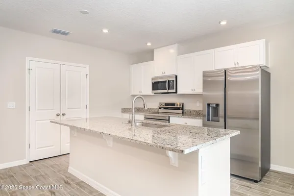a kitchen with kitchen island granite countertop a sink stove and refrigerator