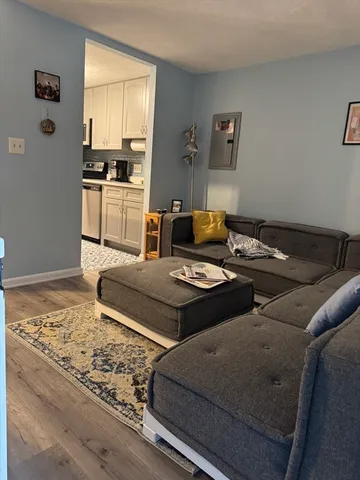 a living room with stainless steel appliances furniture a rug and a window