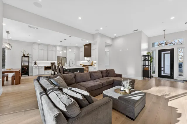 a living room with furniture kitchen view and a chandelier