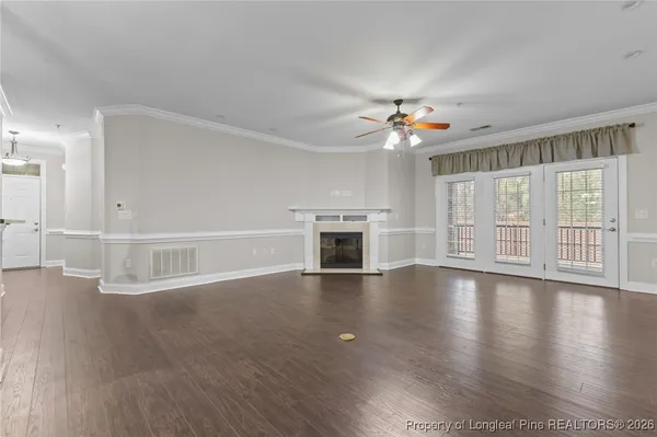 an empty room with wooden floor fireplace and windows
