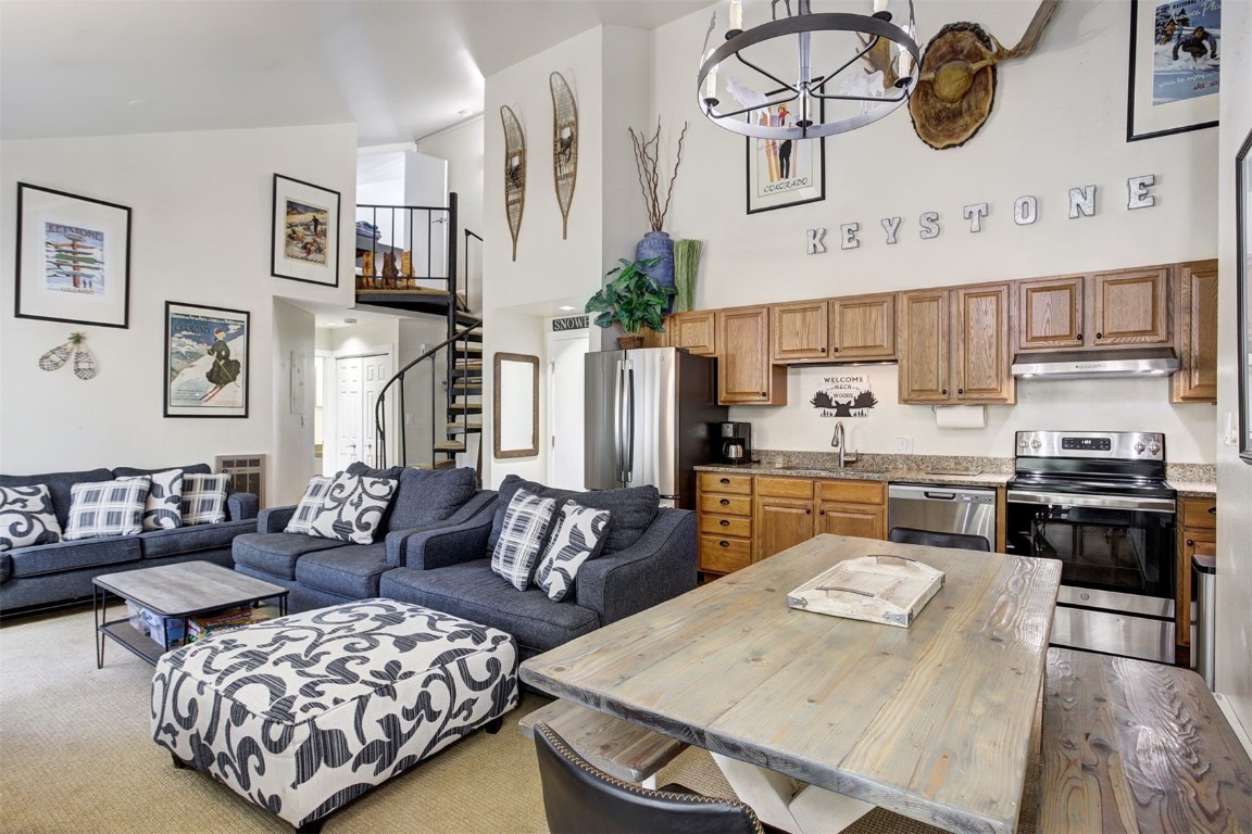 a living room with stainless steel appliances furniture and a kitchen view