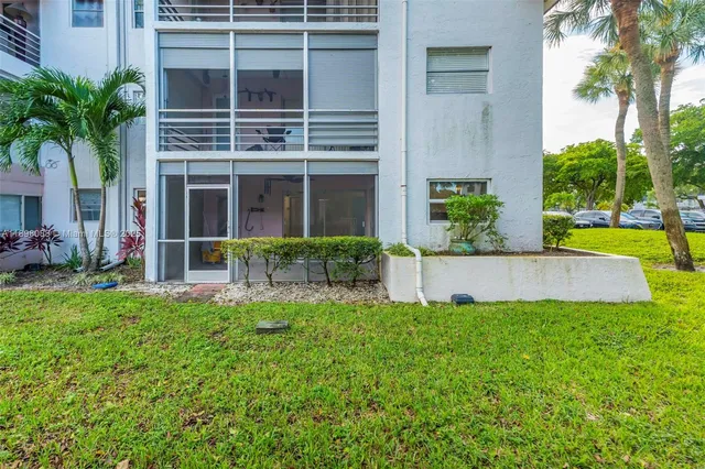 a view of a house with a yard and a large tree