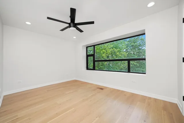 a view of empty room with wooden floor and fan