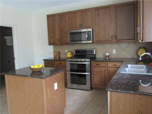 a kitchen with stainless steel appliances granite countertop a sink and a stove top oven