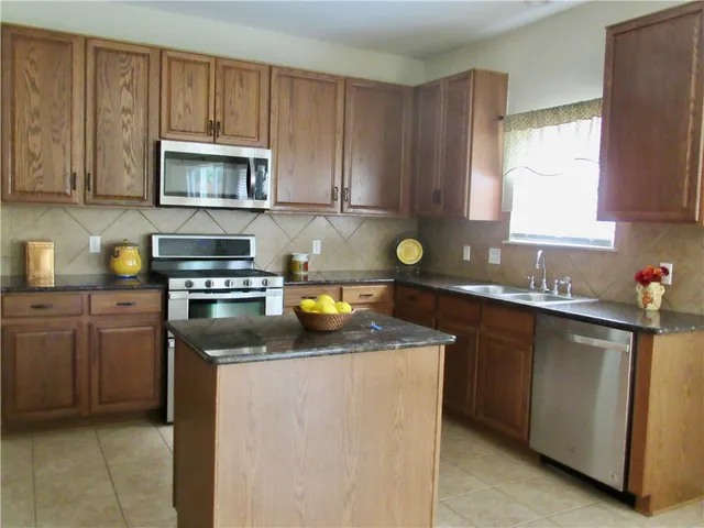 a kitchen with stainless steel appliances granite countertop a sink stove and microwave