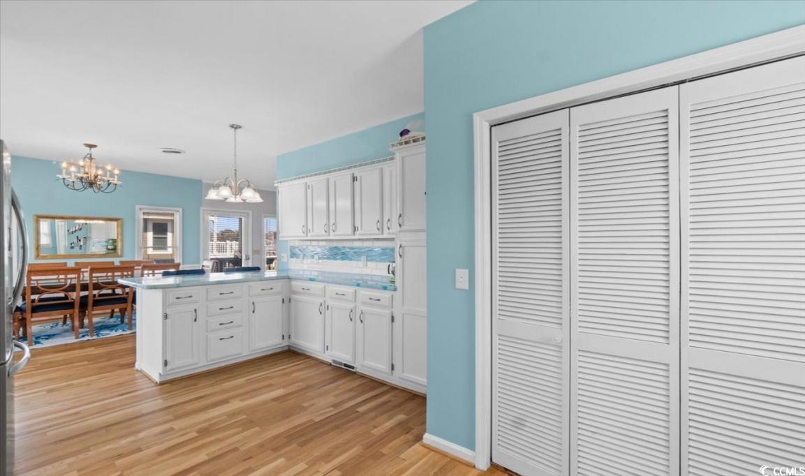 154 SandDollar Drive Holden Beach, NC 28462 - Photo 10 of 39 Kitchen featuring a chandelier, a peninsula, white