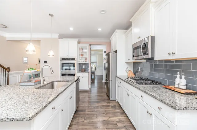 a large kitchen with stainless steel appliances granite countertop a lot of counter space and wooden floors