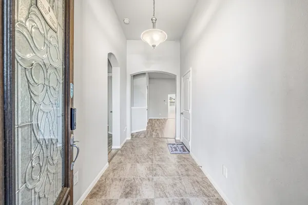 a view of a hallway with wooden floor and a chandelier