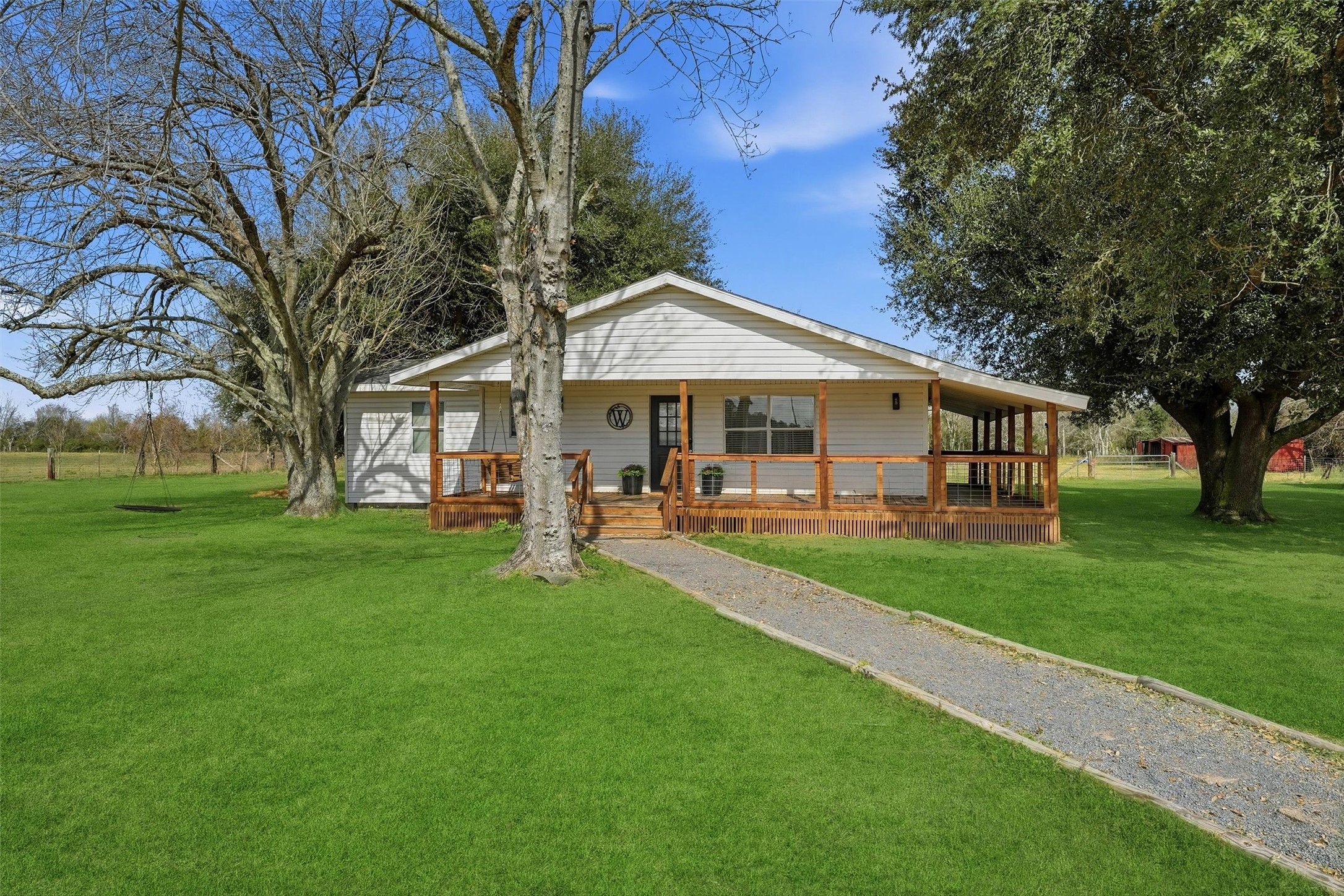 a view of a house with a big yard potted plants and large tree