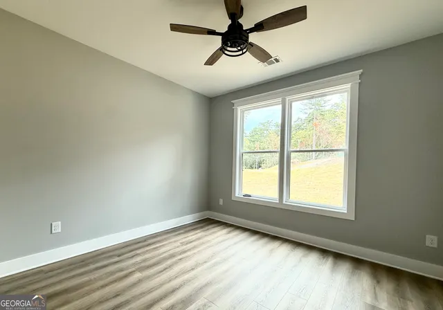a view of an empty room with a window and wooden floor