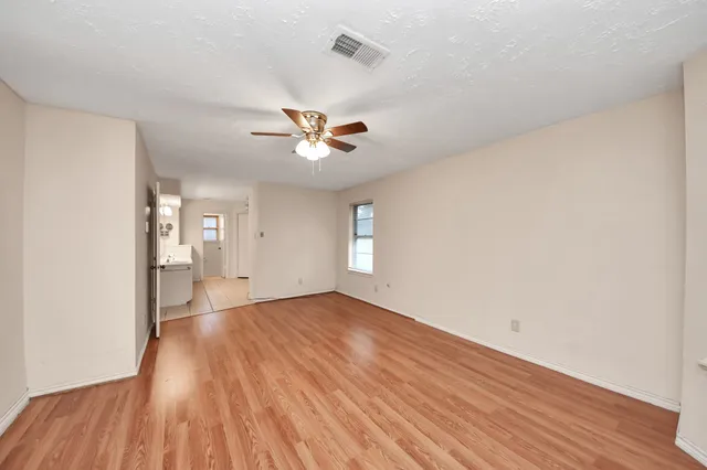a view of an empty room with a window and wooden floor