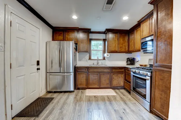 a kitchen with a refrigerator a stove top oven a sink and dishwasher with wooden floor