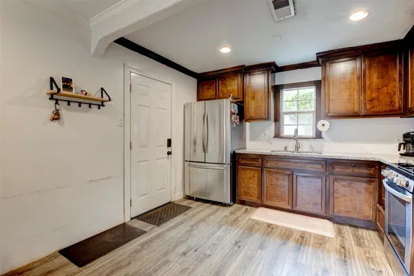 a kitchen with stainless steel appliances granite countertop a refrigerator a sink dishwasher a stove with wooden cabinets and floor