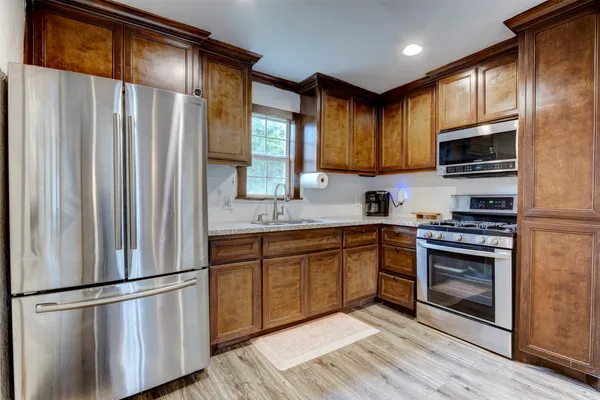 a kitchen with stainless steel appliances granite countertop a refrigerator stove top oven and sink