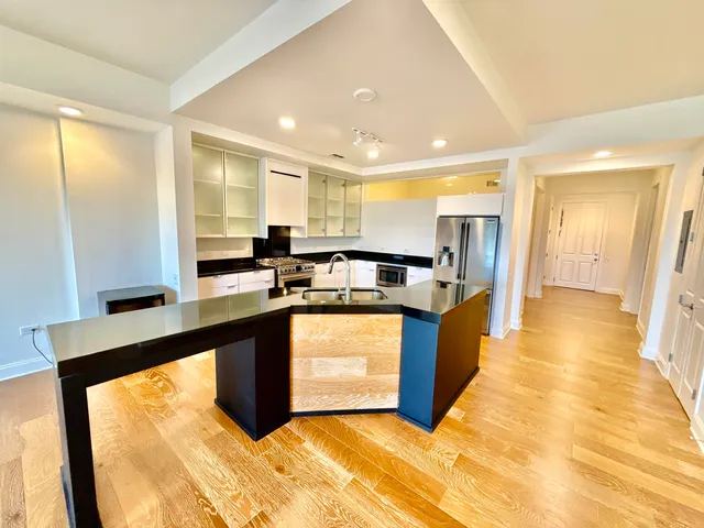a large kitchen with kitchen island granite countertop a sink a counter top space and stainless steel appliances