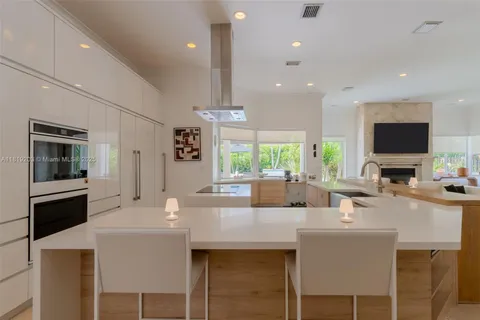 a dining hall with stainless steel appliances kitchen island granite countertop a stove a sink a dining table and chairs with wooden floor