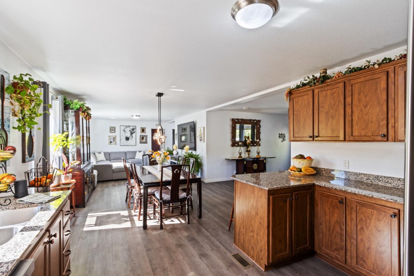 37200 Nason Road, Unit 18 Carmel Valley, CA 93924 - Photo 18 of 71 a kitchen with granite countertop a stove a sink dishwasher a dining table and chairs with wooden floor