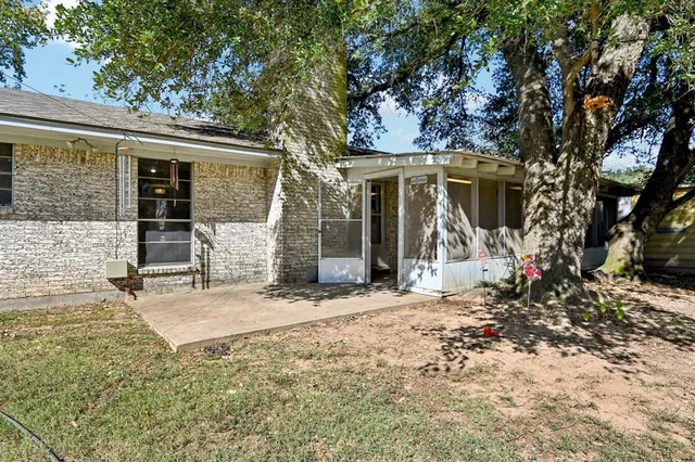 a view of a house with large tree and wooden fence