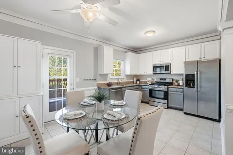 a kitchen with a refrigerator a stove a dining table and chairs