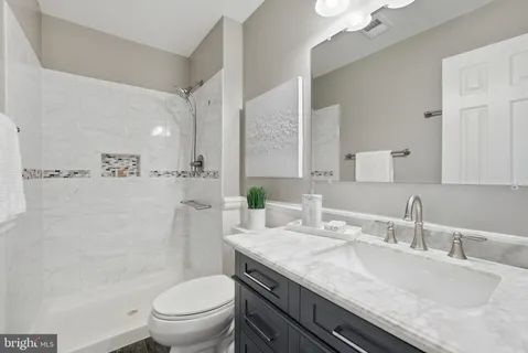 a bathroom with a granite countertop toilet sink and mirror