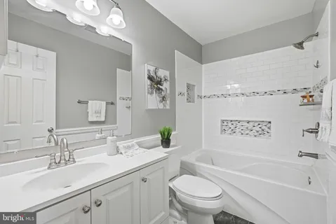 a bathroom with a granite countertop sink a toilet a mirror a bathtub and shower