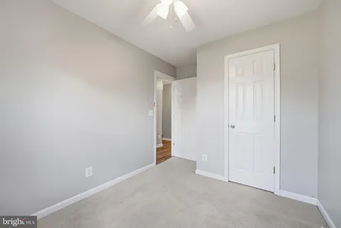 a view of an empty room and chandelier fan