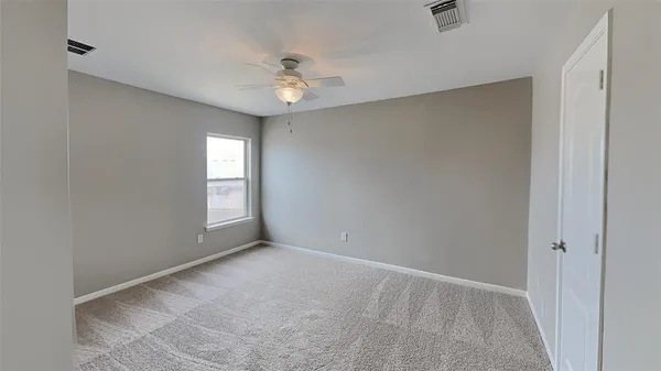 an empty room with windows and fan