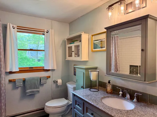 a bathroom with a granite countertop toilet a sink and a mirror